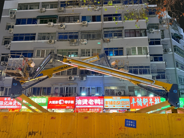 穿街过巷的“刷新艺术家”！豪利777电动直臂高空作业平台精准施技丰储街刷新
